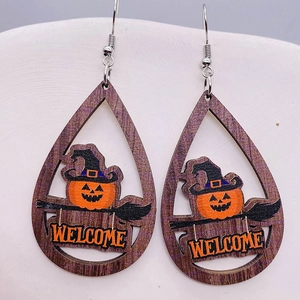 Dettaglio ravvicinato di orecchini in legno di Halloween con zucca e cappello da strega