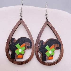 Dettaglio di orecchini a goccia in legno con silhouette artistica e motivo floreale verde