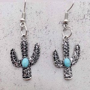 Gros plan de boucles d'oreilles cactus bohèmes avec pierre turquoise et fini argenté