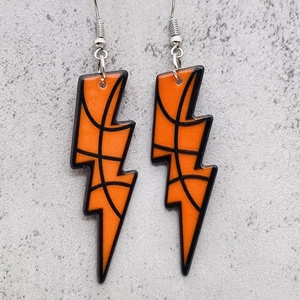 Détail de boucles d'oreilles en acrylique en forme d'éclair avec motif basket orange