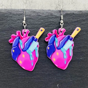 Gothic acryl hart oorbellen met geel mes en bloeddruppels op een stenen achtergrond