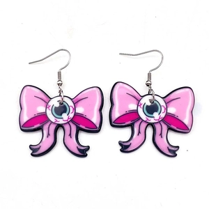 Dettagli macro di orecchini a bulbo oculare con fiocchi rosa glitterati e ganci argentati
