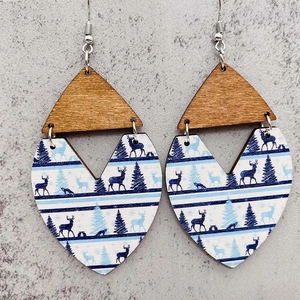 Primer plano de pendientes bohemios de madera con motivos de alces y bosque en forma de corazón
