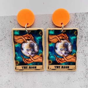 Macro shot of tarot moon earrings with orange acrylic stud and detailed artistic graphics
