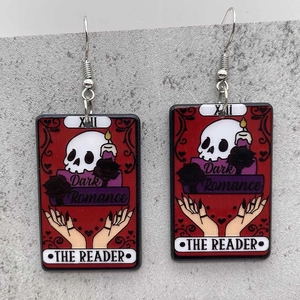 Detail of gothic tarot card earrings with skull, black roses, and XII dark romance print
