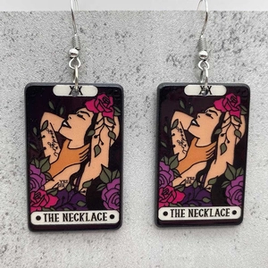 Detail of tarot card style acrylic earrings featuring rose and female profile graphics