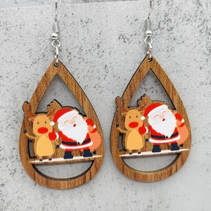 Detalle de pendientes de madera en forma de gota con dibujos de Papá Noel y renos