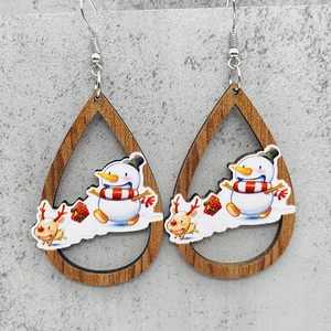 Detalle macro de pendientes de madera en gota con estampados festivos navideños