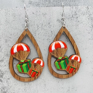 Detalle macro de pendientes de madera en forma de gota con motivos de paracaídas y regalos