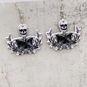 Gotische Acryl-Ohrringe mit Totenkopf und Buch an Silberhaken auf grauem Steingrund