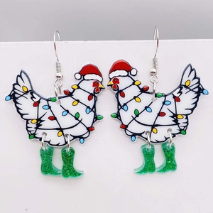 Gros plan sur les boucles d'oreilles poule de Noël en acrylique avec bottes vertes