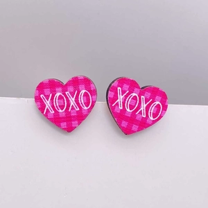 Detalle de pendientes de corazón de madera rosa con diseño XOXO y textura de rejilla