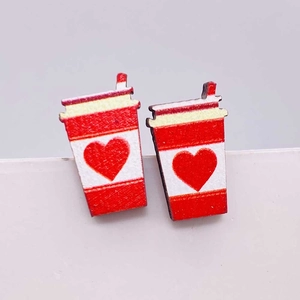 Macro de pendientes de tazas de café con corazón en un soporte blanco minimalista