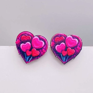 Detalle de pendientes de corazón con capas de resina en tonos rosa y rojo brillante