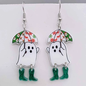 Close-up of cute white ghost Christmas earrings with festive umbrella and green glitter boots