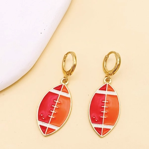 Détail de boucles d'oreilles rugby avec émail rouge et orange et crochets dorés