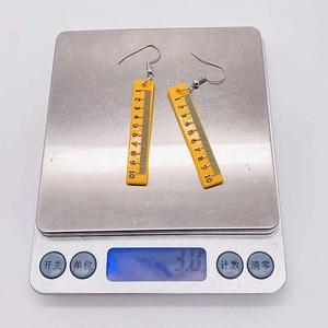 Detailed view of yellow ruler earrings on digital scale showing a weight of 3.0g