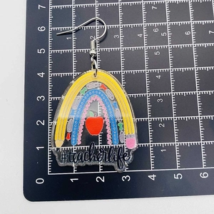Acrylic rainbow earrings for teachers with pencils and ruler on a grid background