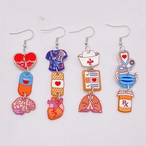 Macro view of medical-themed earrings with stethoscope, red heart and nurse uniform details