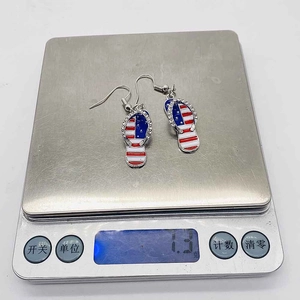 Dettaglio del peso di 1,3g degli orecchini a infradito con bandiera USA sulla bilancia