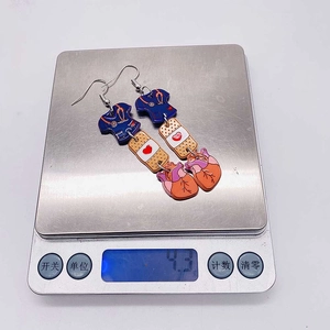 Detail shot of medical themed acrylic earrings weighing 4.3g on an electronic scale