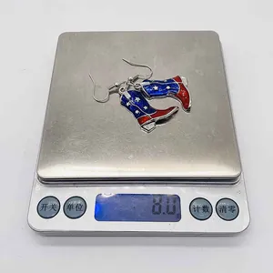 Dettaglio orecchini a stivale da cowboy con bandiera USA e peso di 8,0g sulla bilancia