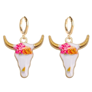 Detalle de pendientes de calavera de toro con patrón floral y cuernos dorados metálicos