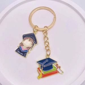 Golden enamel graduation keychain with cartoon graduate and academic book pendants