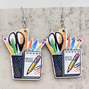 Detail of wooden back to school earrings featuring pencils and scissors elements