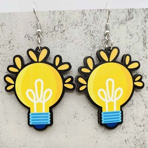 Detailed top view of creative yellow light bulb earrings with blue base on grey surface