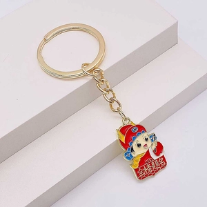Close-up of golden graduation keychain with red cartoon scholar and success charm