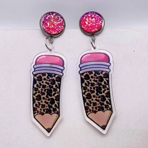 Détail de boucles d'oreilles crayon léopard avec paillettes roses pour enseignants