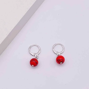 Detail of silver hoop earrings featuring red marble textured round bead charms and clasp closure