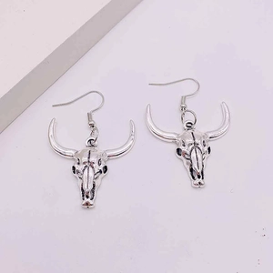 Close-up of vintage silver bull skull earrings with distressed metal texture and hooks