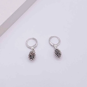 Detail of vintage pine cone pendant earrings with realistic texture in silver finish