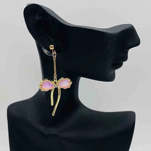 Boucles d'oreilles nœud dorées avec opales roses et rubans sur présentoir noir