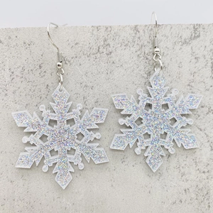 Close-up of snowflake earrings with sparkling silver glitter and acrylic texture