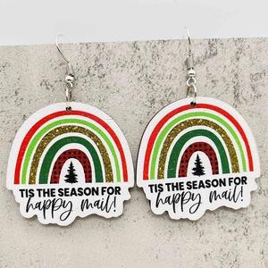 Makroansicht regenbogenförmiger Weihnachts-Ohrringe mit Festtagsgrüßen und Tannenbaum-Motiv