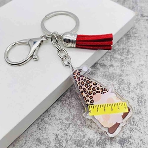 Detail shot showing 5cm width measurement of leopard print gnome acrylic keychain with red tassel