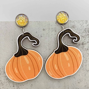 Detalle de pendientes de calabaza otoñales con botón de purpurina y diseño festivo
