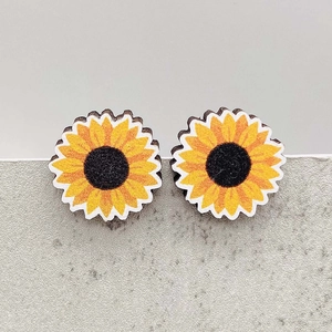 Detail view of sunflower-shaped wood earrings with vibrant yellow petals and textured centers