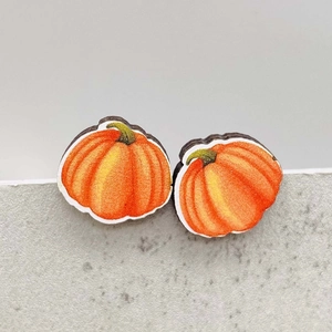Macro detail of pumpkin shaped wooden earrings with vibrant autumn orange gradients