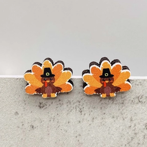 Detailed view of turkey-shaped wooden earrings with autumn colors and pilgrim hat decor