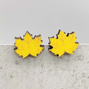 Detailed macro shot of yellow maple leaf wooden earrings with fine engraved leaf veins