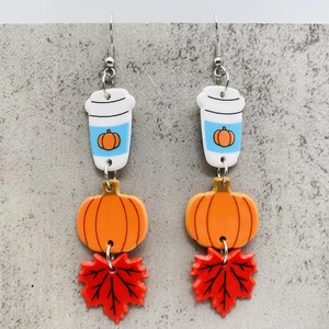 Detail of fall-themed earrings featuring acrylic pumpkin, maple leaf, and coffee cup