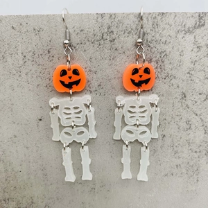 Halloween pumpkin earrings with movable skeleton drop design on a grey stone texture