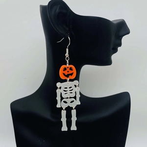 Detail of Halloween drop earrings with orange pumpkin face and white skeleton body parts