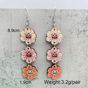 Halloween wooden drop earrings with pumpkin faces and measurement specs on stone background