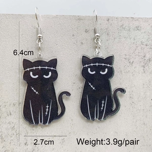 Macro view of spooky black acrylic cat earrings with white stitch detail for Halloween