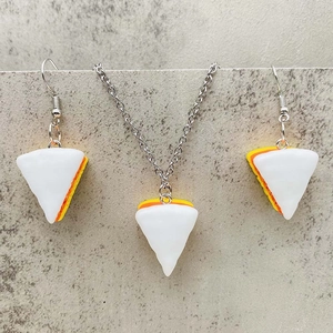 Dreiteiliges Schmuckset mit Candy Corn Harzanhängern auf texturiertem Steinuntergrund